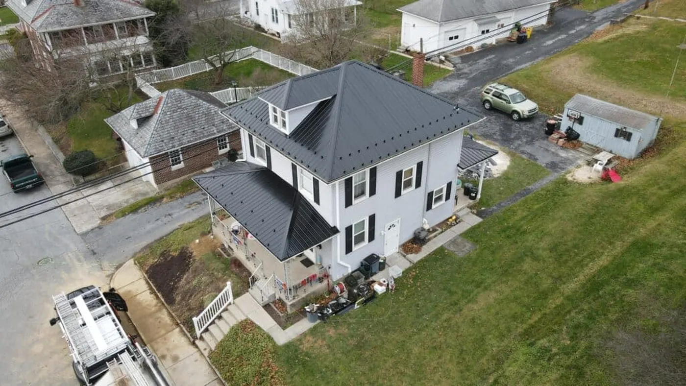 Aerial view of a completed dark metal roof on a white home