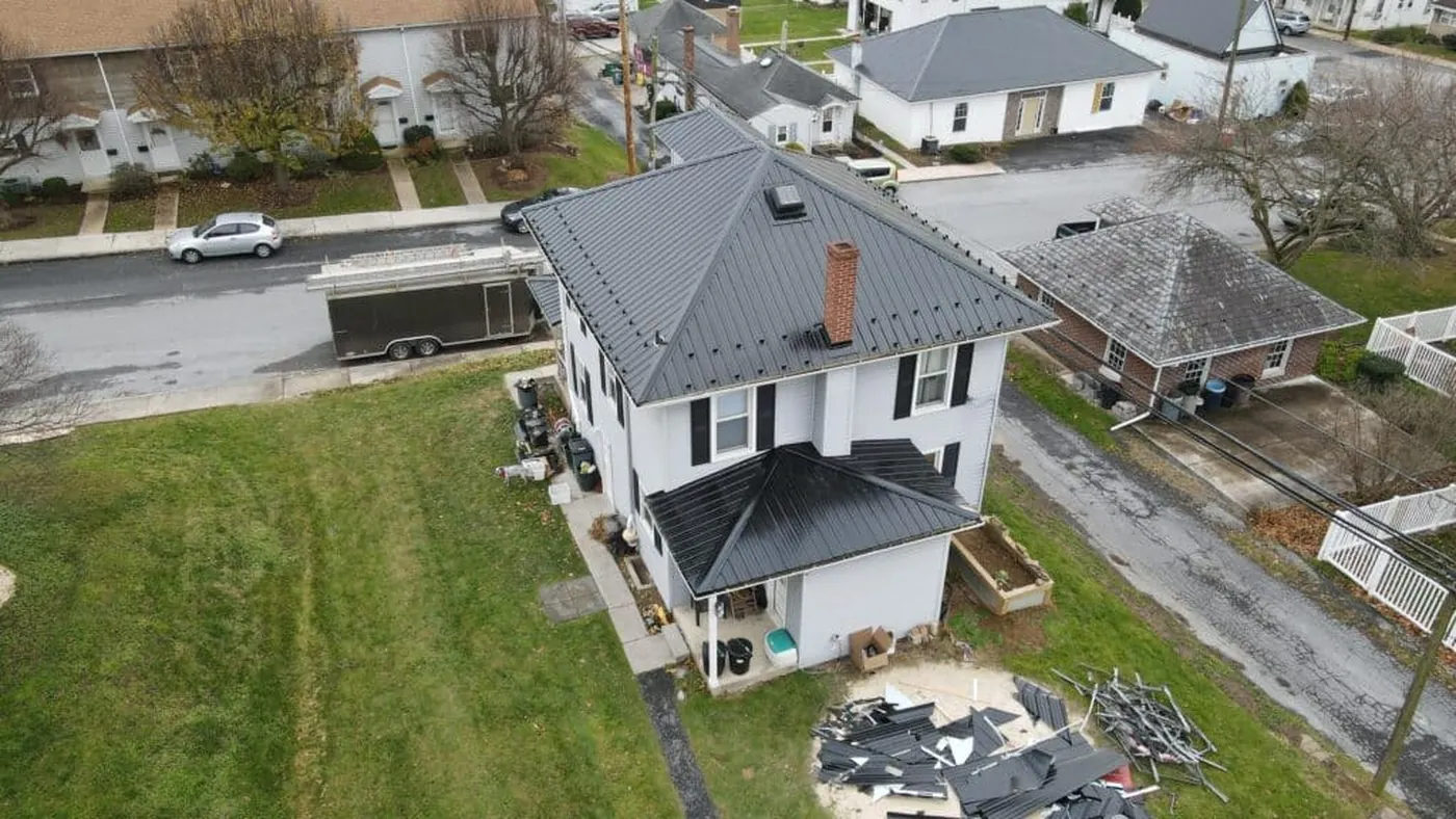 Aerial view of a completed metal roof on a white home