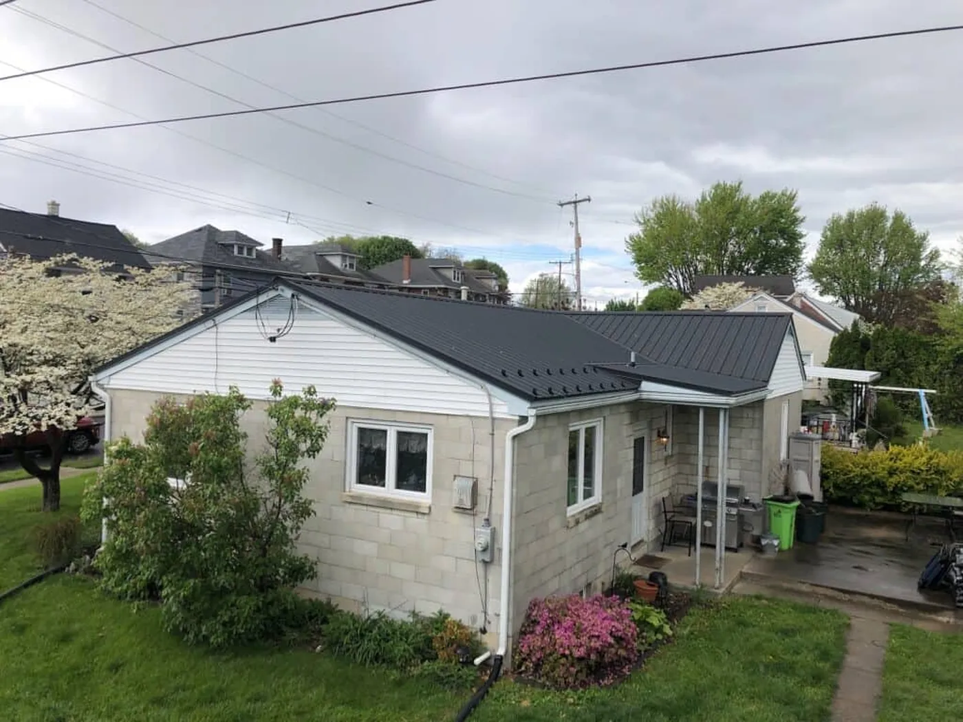 Gray metal roof viewed beside flowering trees